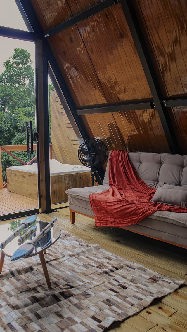 Interior do chalé — sala aconchegante com deck e natureza